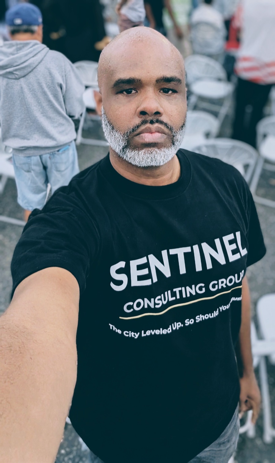 Wilson L. Holts III wearing a Sentinel Consulting Group shirt reading &lsquo;The City Leveled Up, So Should Your Business&rsquo;
